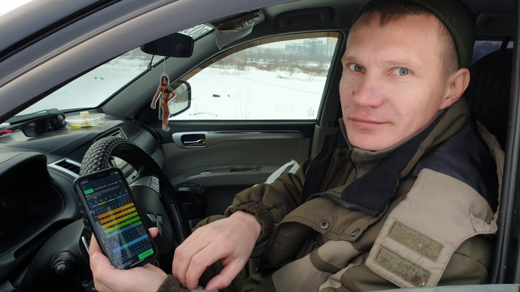Фото: Олег Антонов / Иван Ярцев показывает цветные колонки цифр сайта погоды на смартфоне фото